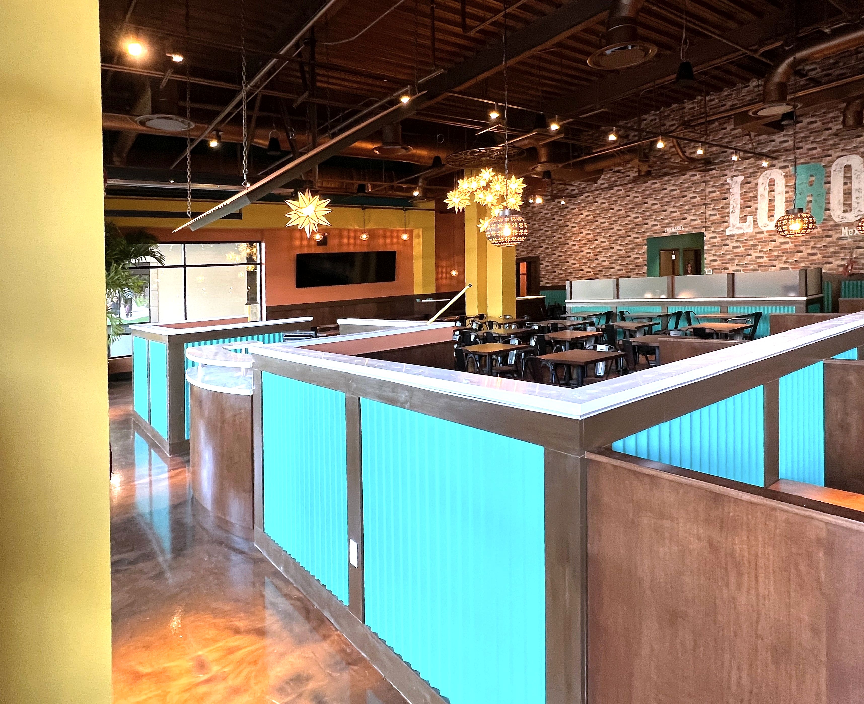 Restaurant interior with teal corrugated booth partitions and star pendant lamps
